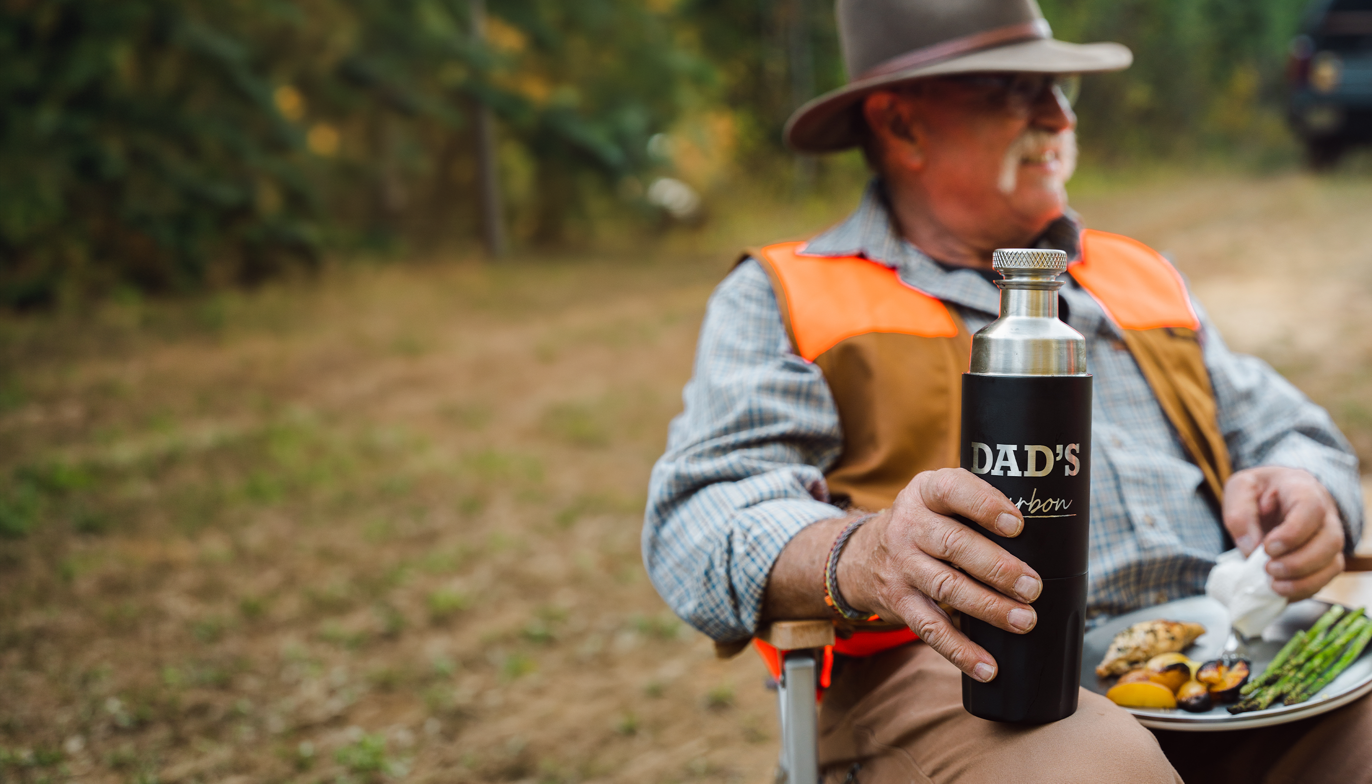 Man in outdoor setting holding a dad bottle.